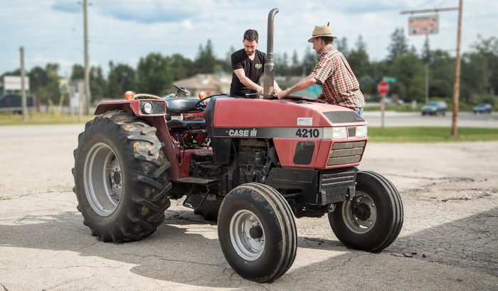 Technician teaching a mennonite farmer about preventative maintenance on his tractor